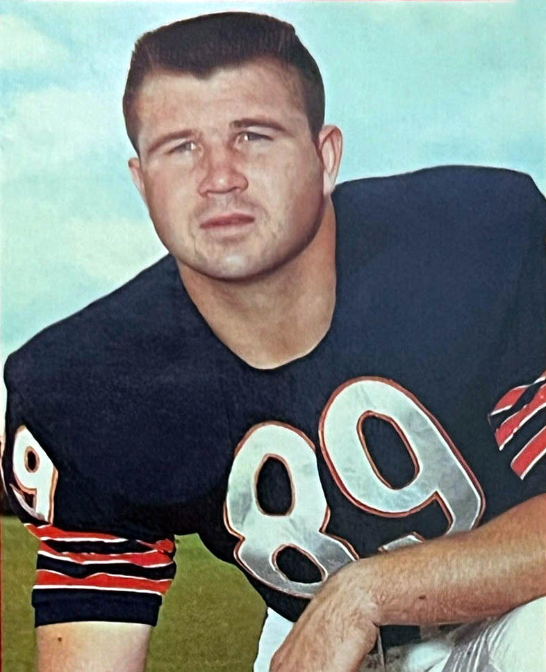 Mike Ditka in a dark Chicago Bears jersey with number 89, kneeling on a football field in a 1963 Topps card photo.